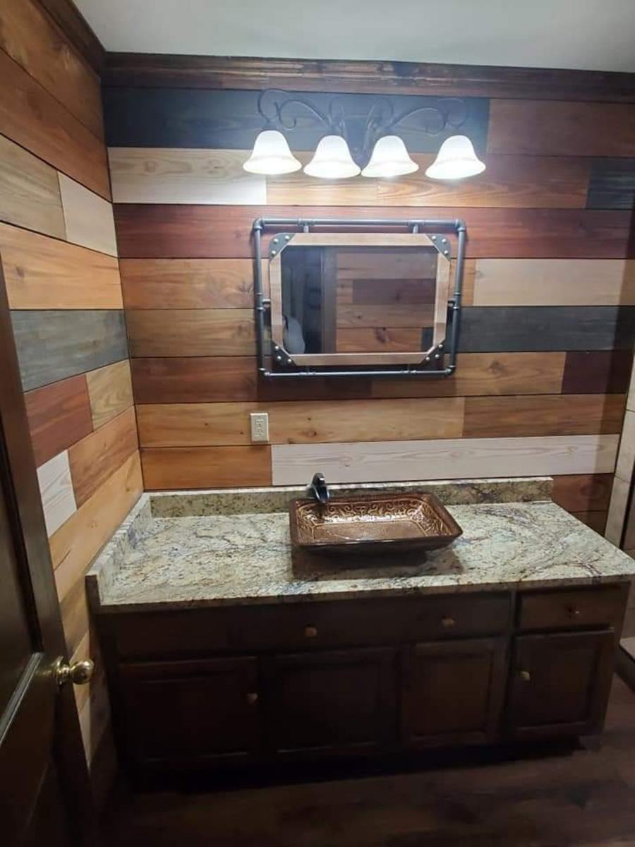 Completed bathroom vanity with wood accent walls, vessel sink, mirror, and light fixture.