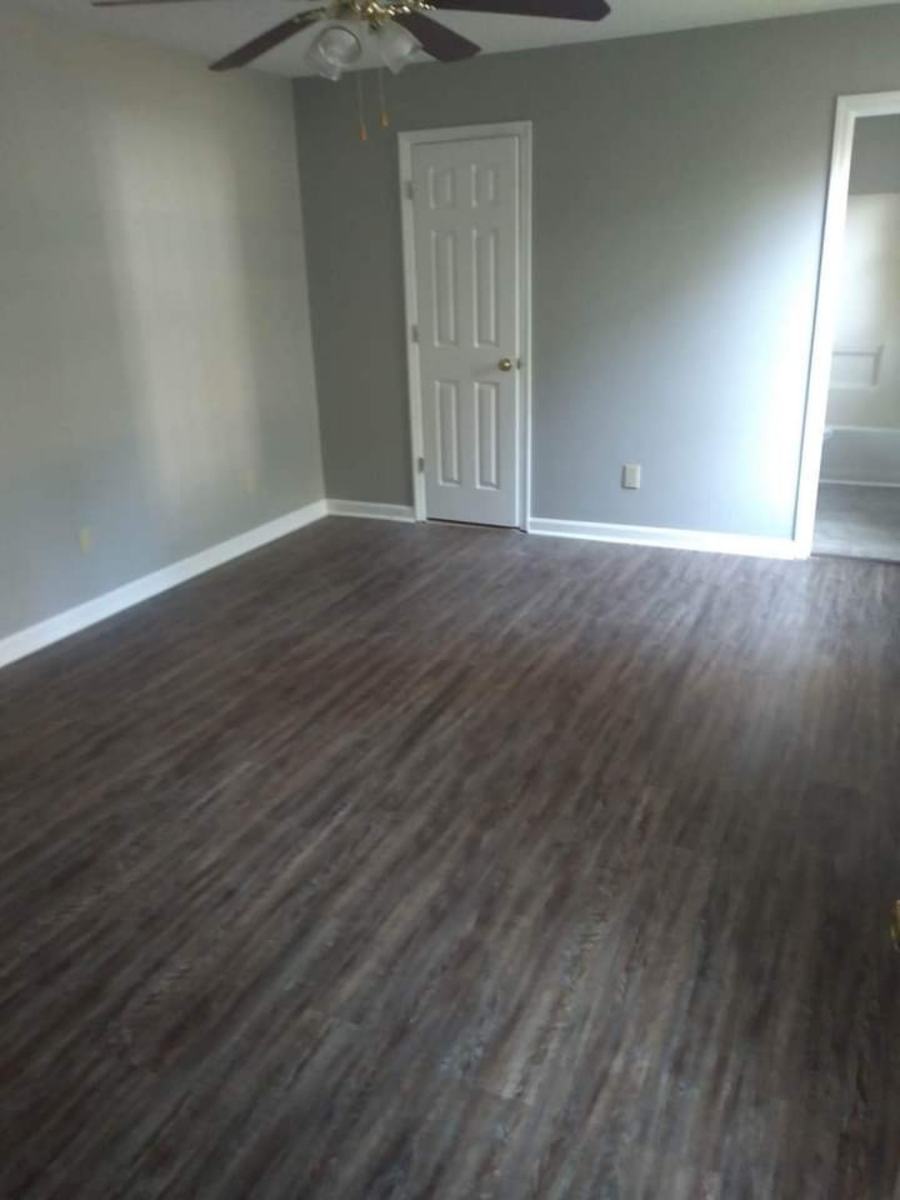 Completed room with dark plank flooring, gray painted walls, white trim, and door casing.